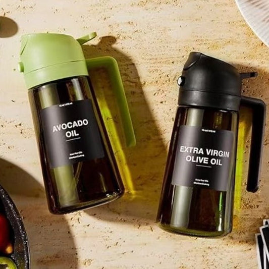 Hand holding glass oil sprayer over frying pan in modern kitchen